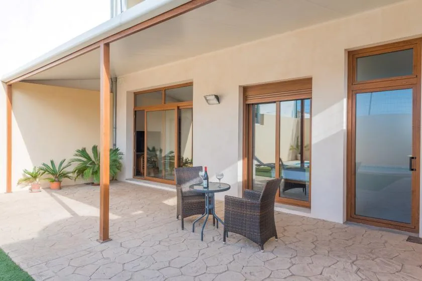 Un patio cubierto con una mesa pequeña, asientos y puertas de vidrio.
