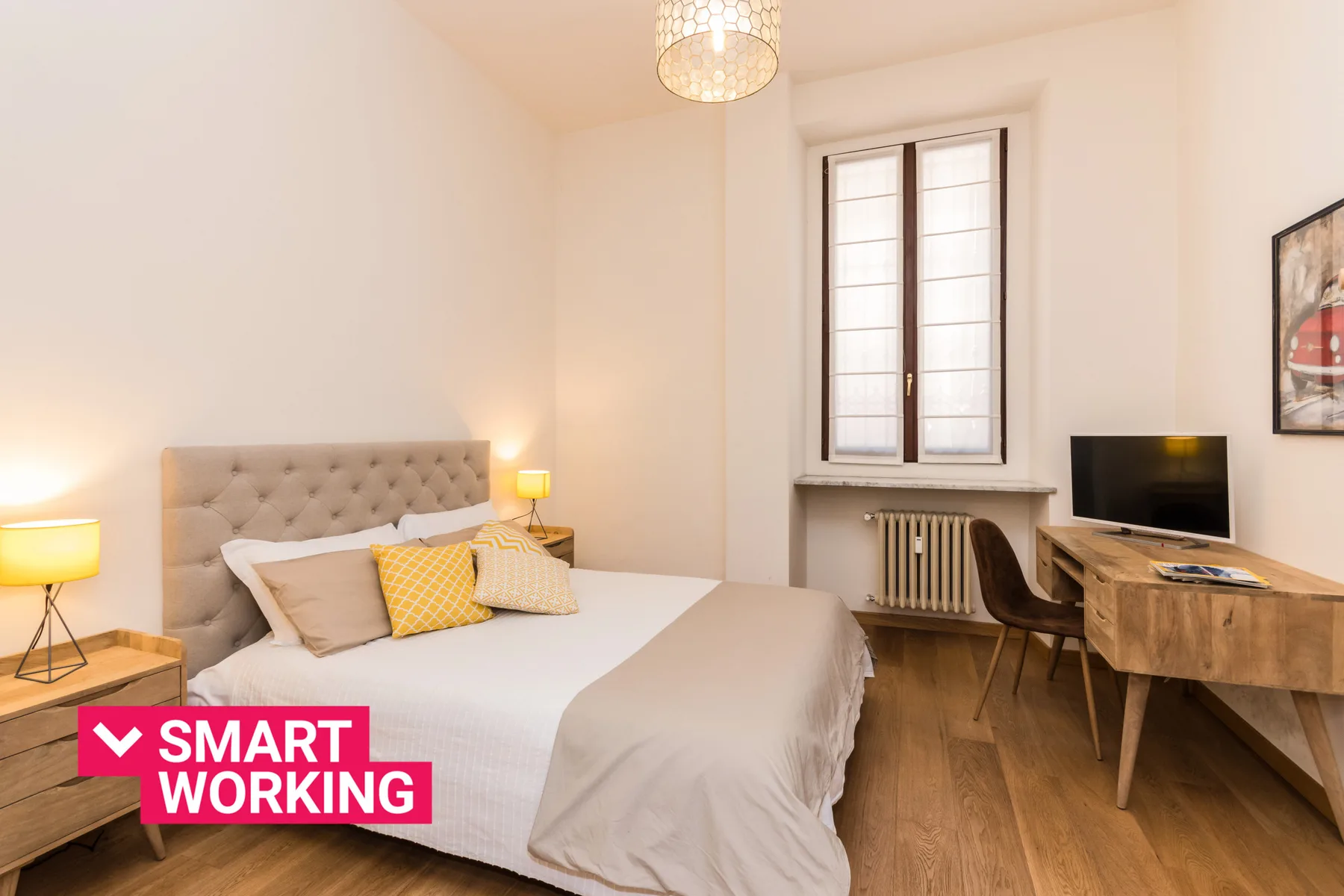 Un dormitorio con cama doble, escritorio y televisor junto a la ventana.