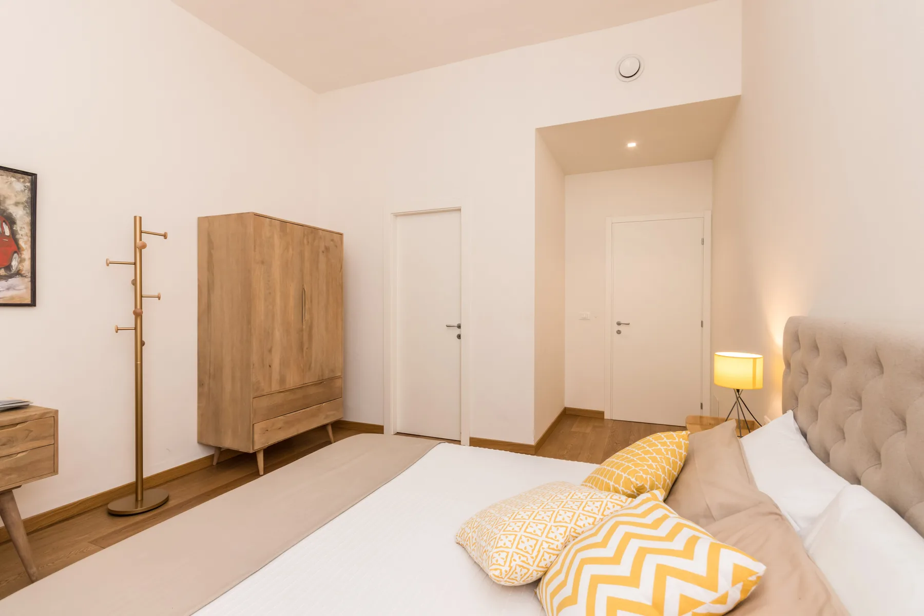 Un dormitorio con una cama, cojines estampados y un armario de madera.