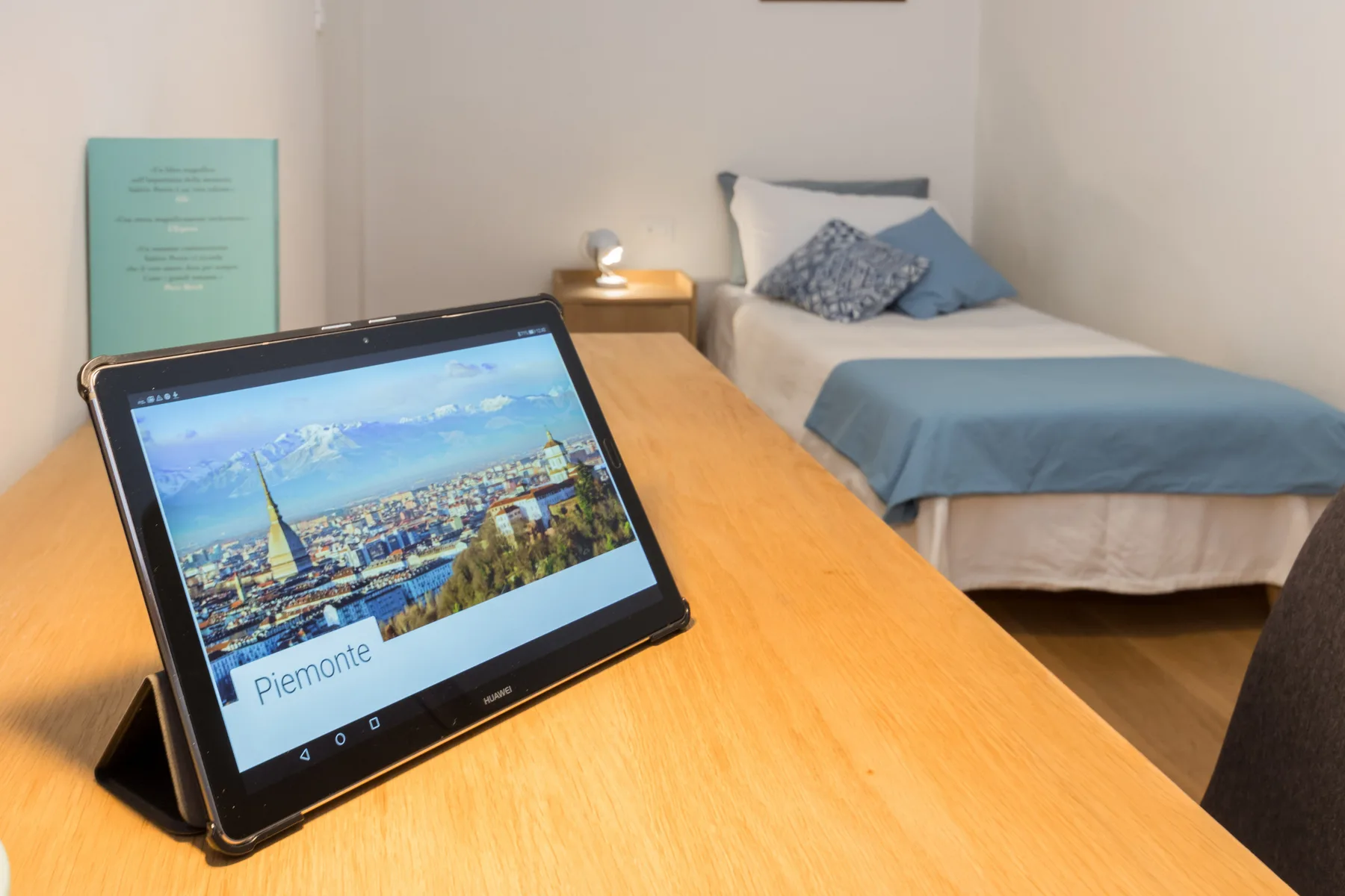 Un dormitorio con una cama individual y una tableta sobre un escritorio de madera.