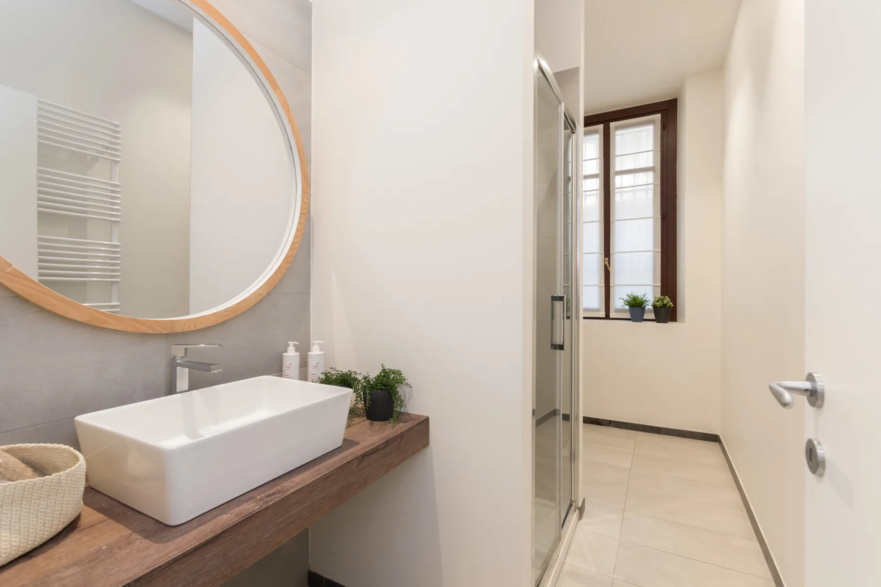 Un baño luminoso con lavabo sobre encimera, espejo grande y ventana.