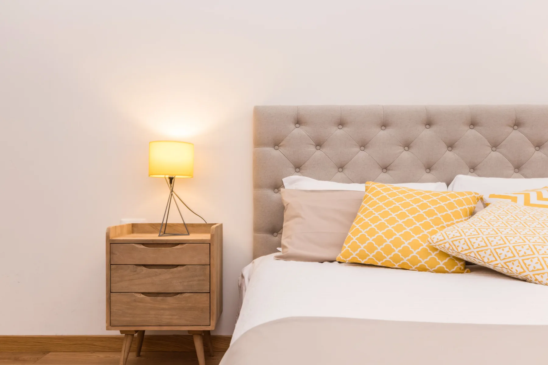 Un dormitorio con una cama, un cabecero capitoné y una lámpara de mesita.