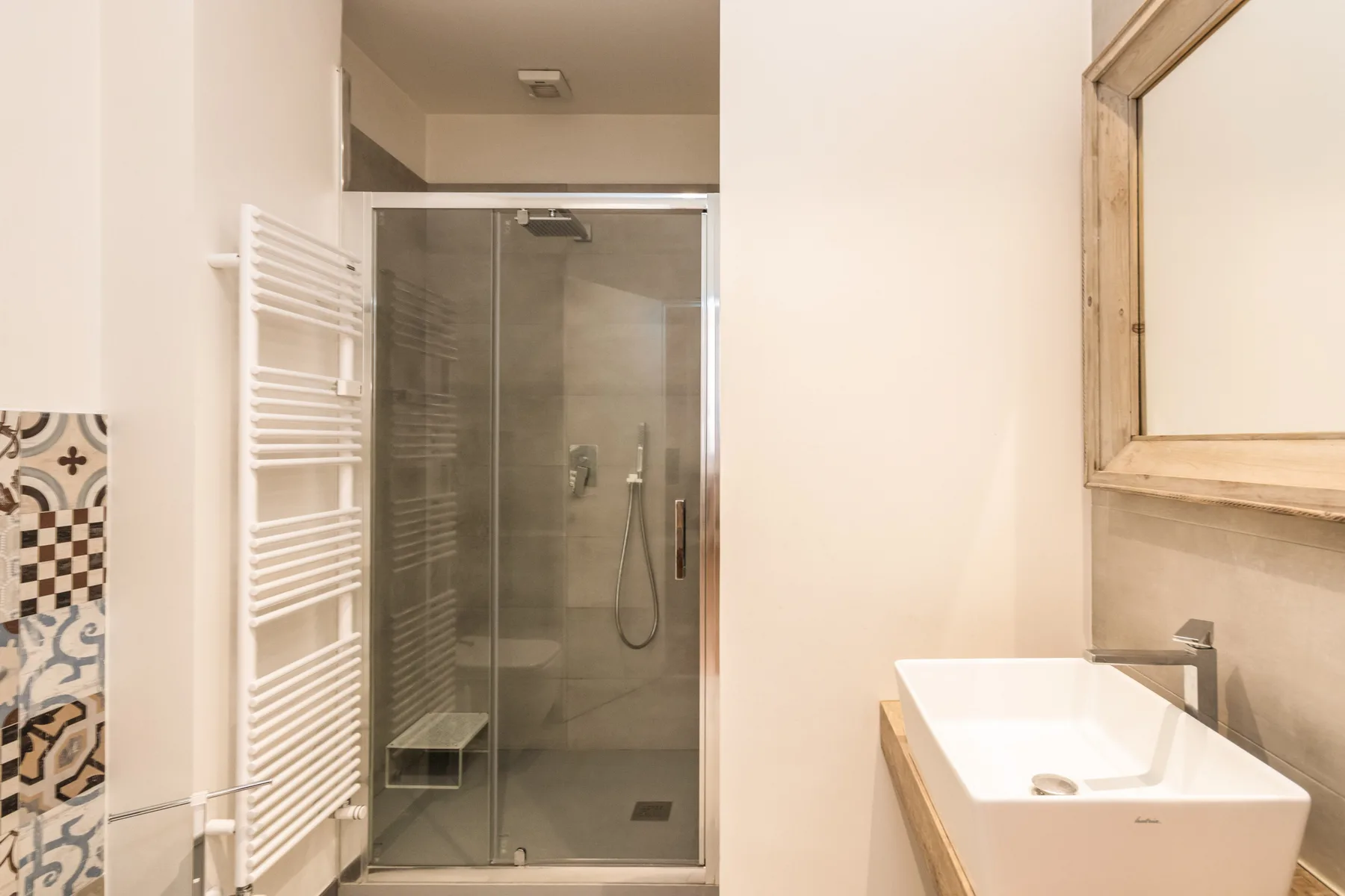 Un baño luminoso con una ducha de vidrio y un lavabo blanco.