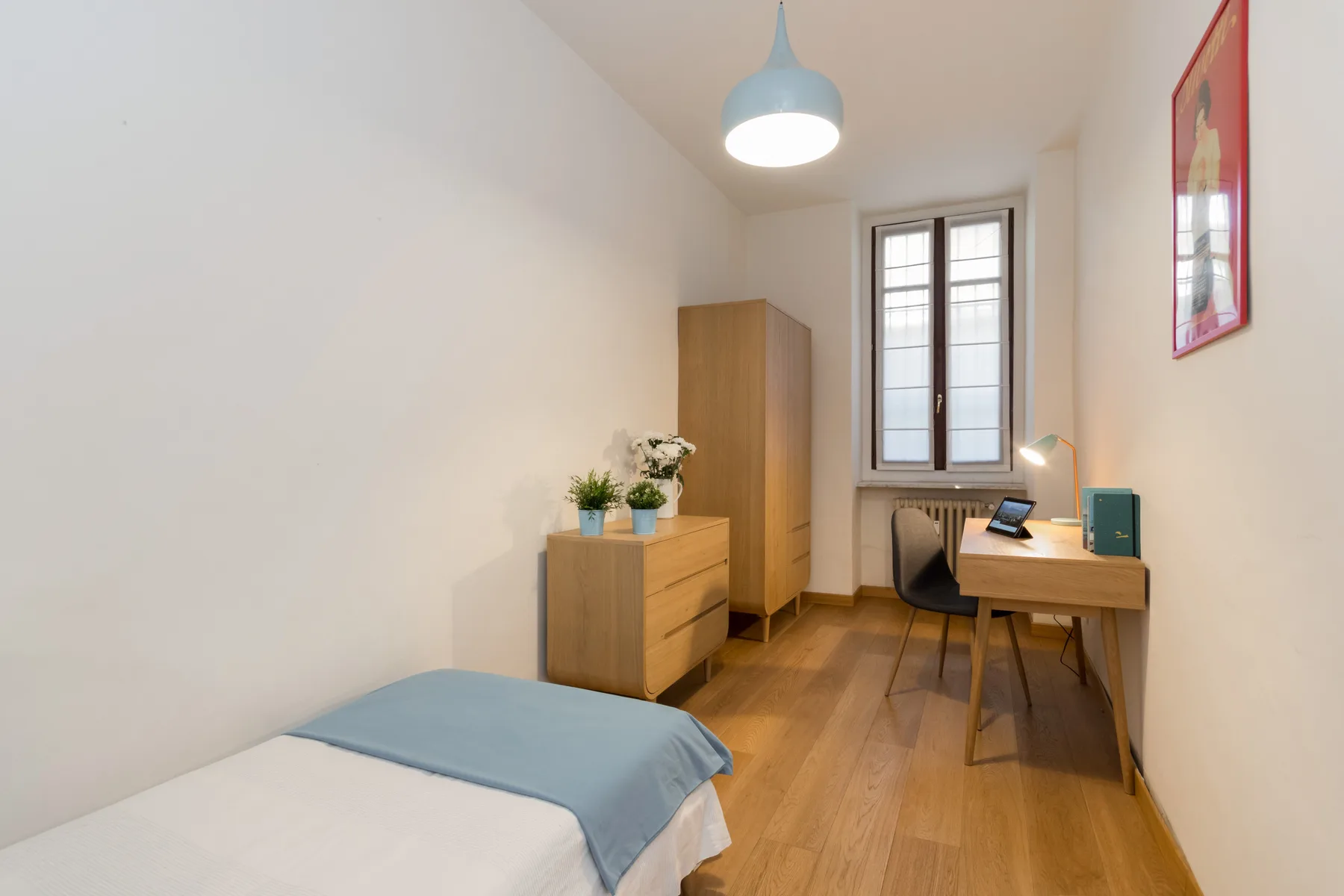 Un dormitorio con una cama, muebles de madera y un escritorio junto a la ventana.