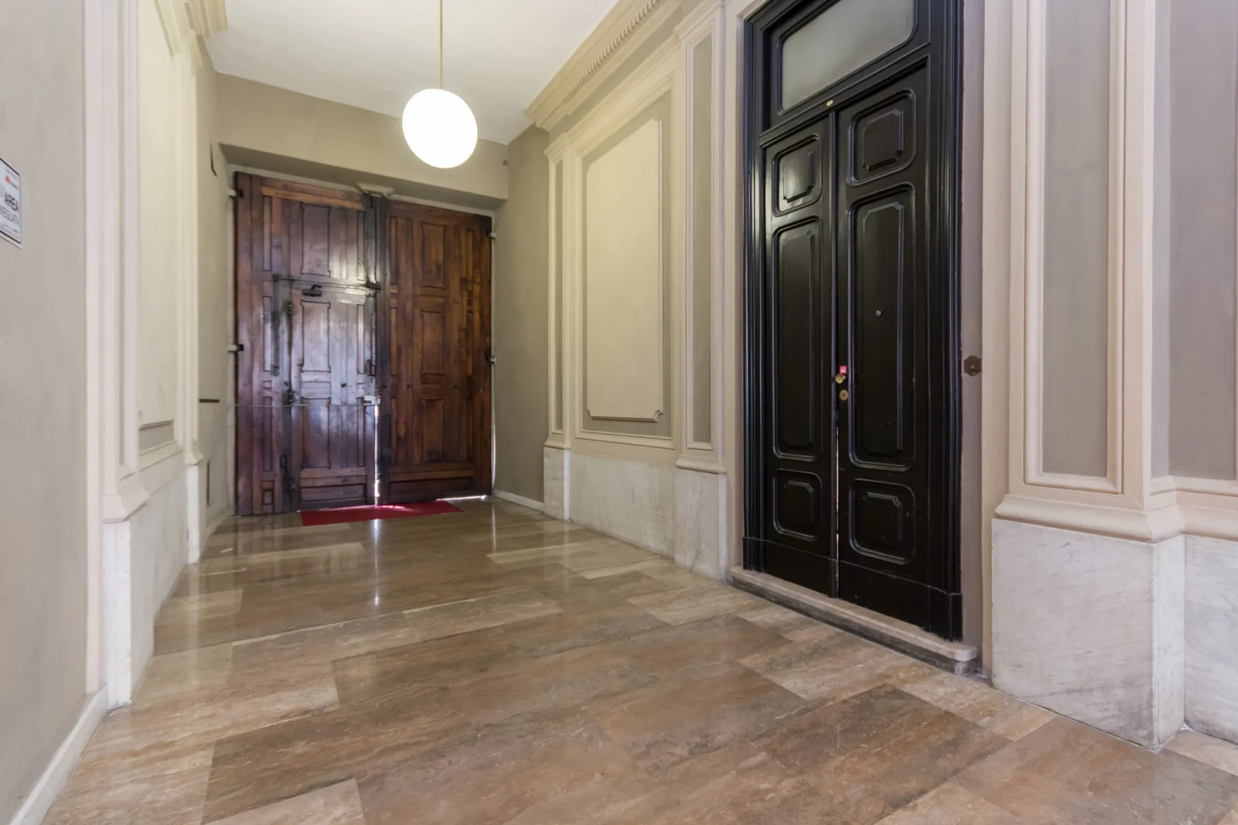 Un pasillo interior con paredes paneladas y puertas de madera oscura.