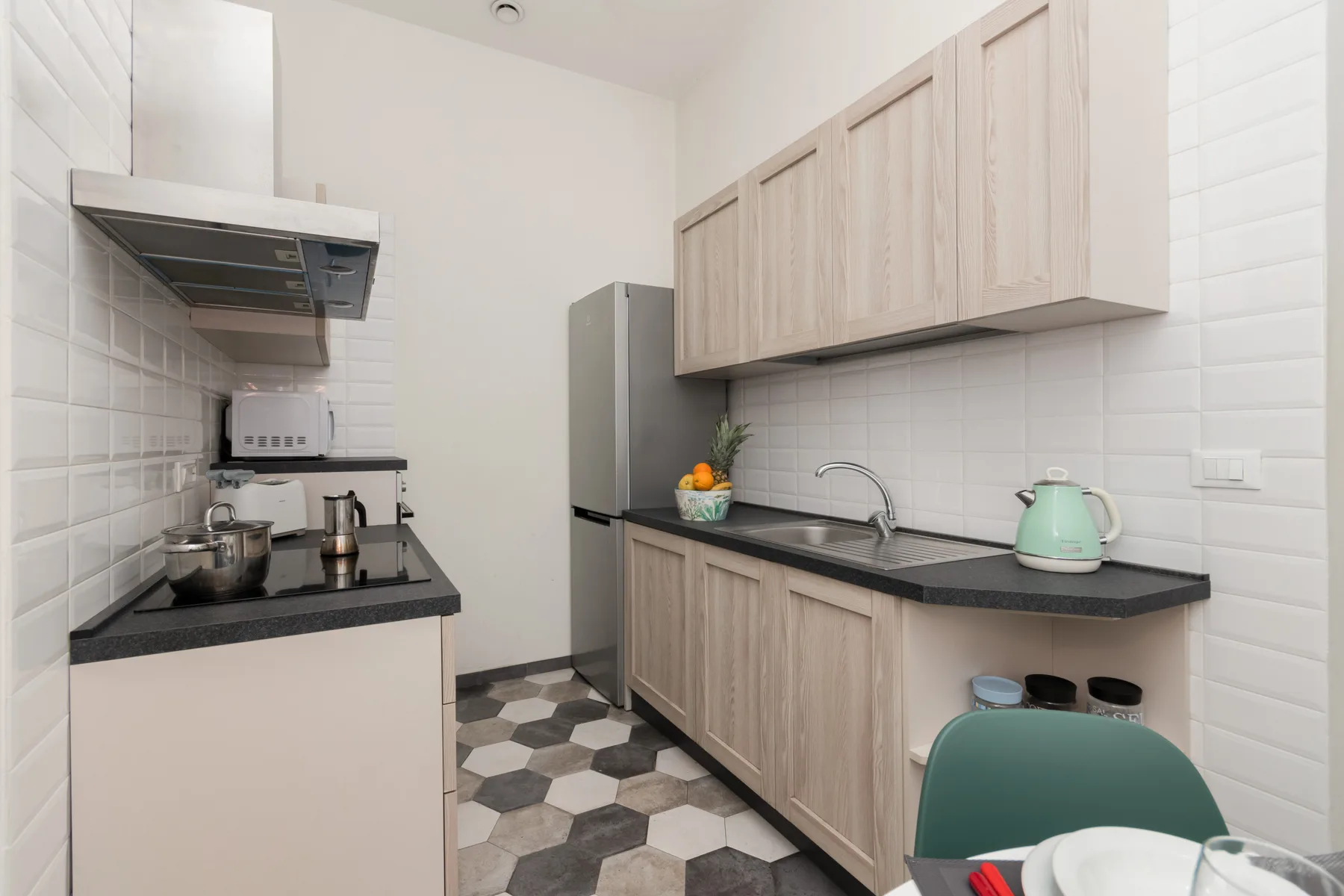 Una cocina compacta con gabinetes de madera clara y encimeras oscuras.