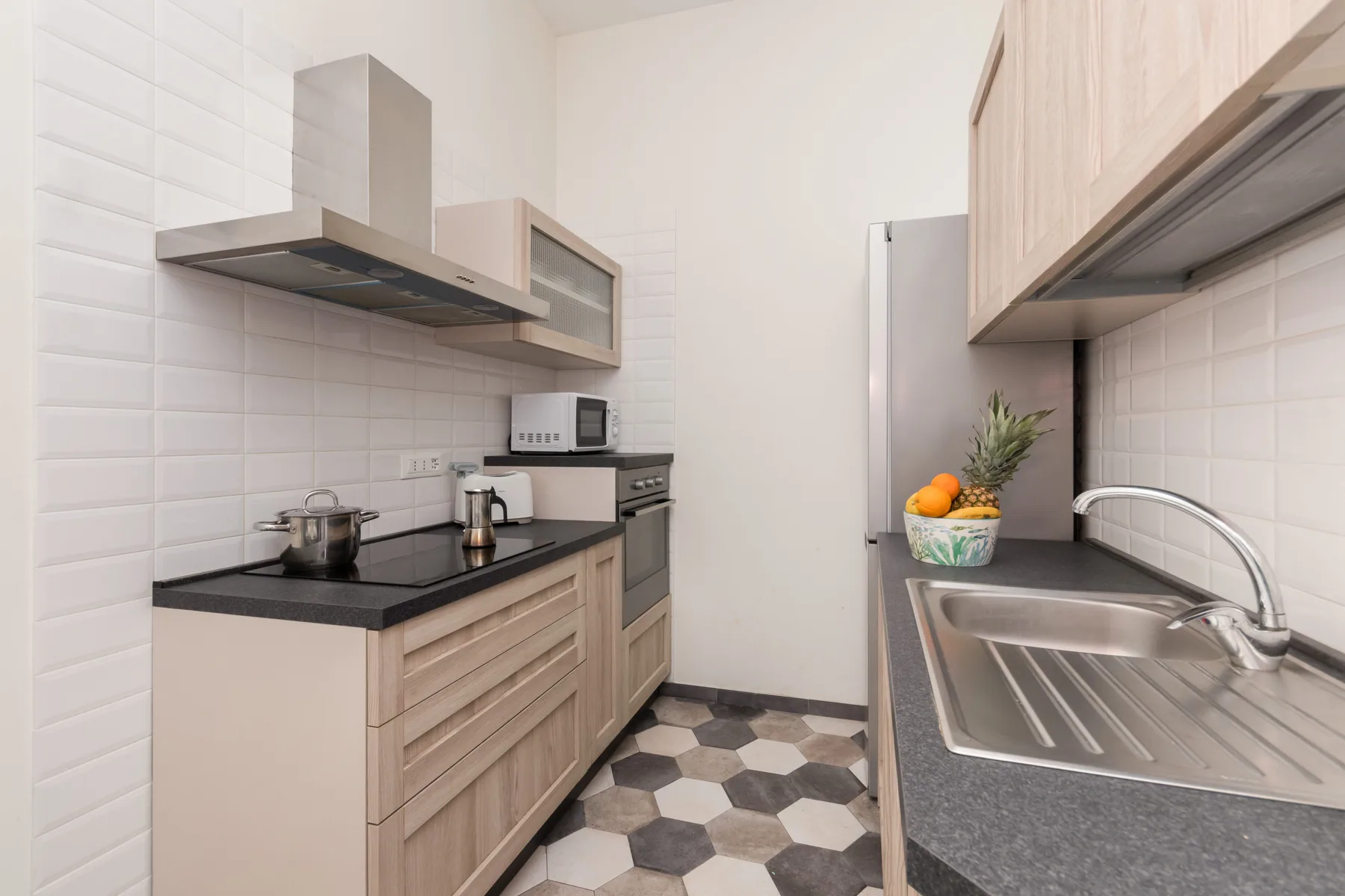 Una cocina moderna con gabinetes claros, encimeras oscuras y un fregadero de acero inoxidable.