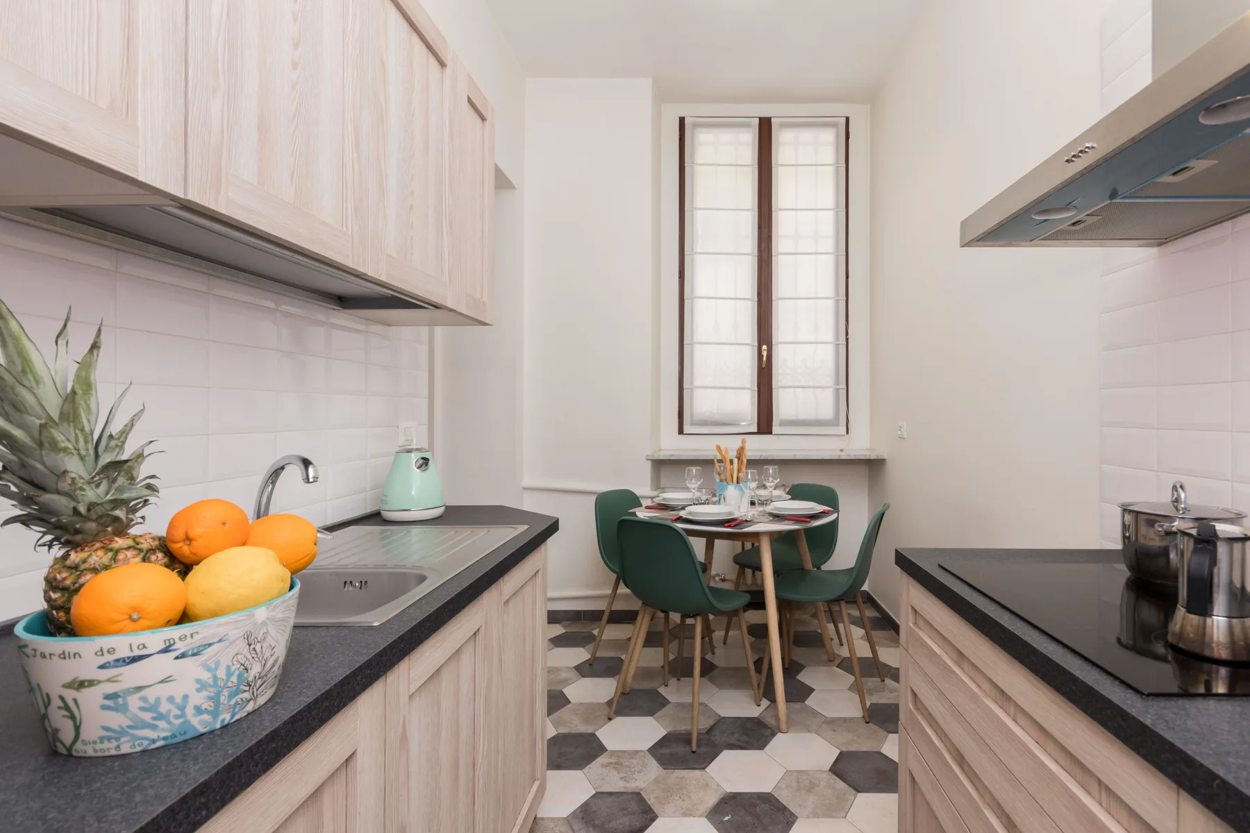 Una cocina estrecha con una pequeña mesa de comedor bajo una ventana.