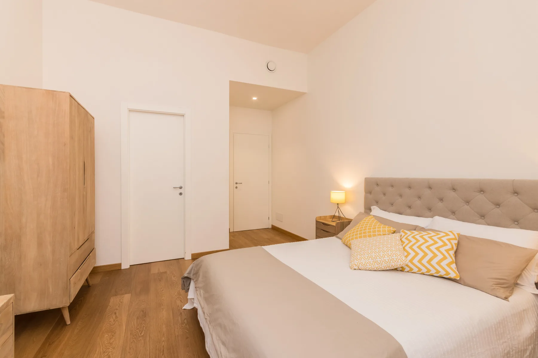 Un dormitorio con una cama, una lámpara de noche y un armario de madera.