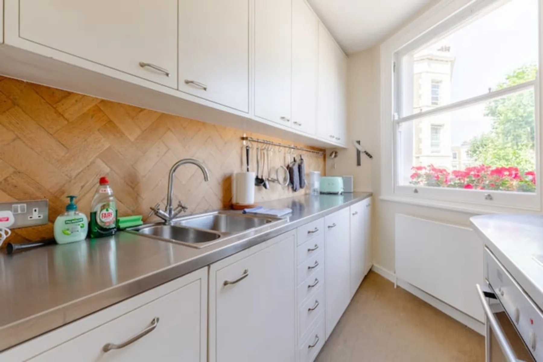 A bright kitchen with white cabinets, a sink, and a large window.