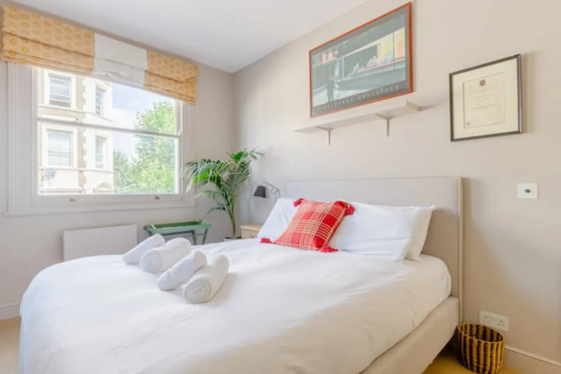 A bright bedroom with a neatly made bed and a large window.