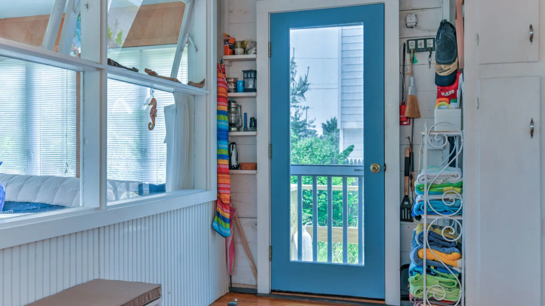 A bright room with a blue-framed glass door opening onto a balcony.