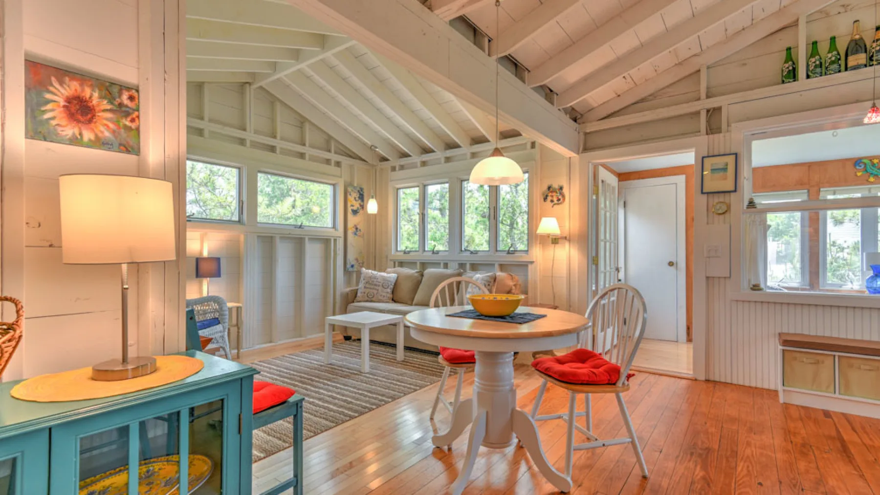 A bright dining area with a round table, chairs, and large windows.