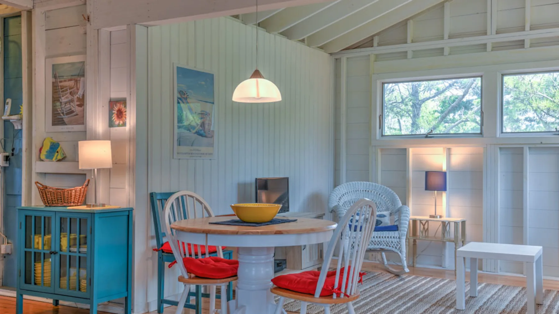 A bright dining and sitting area has a round table and white seating.