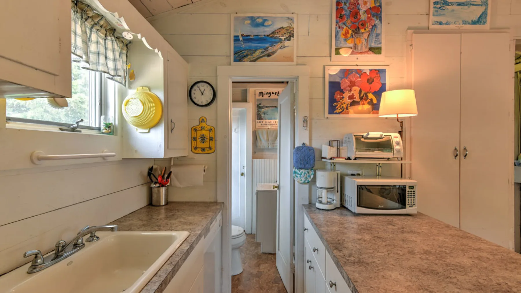 A compact kitchen with counters, a sink, and a microwave.