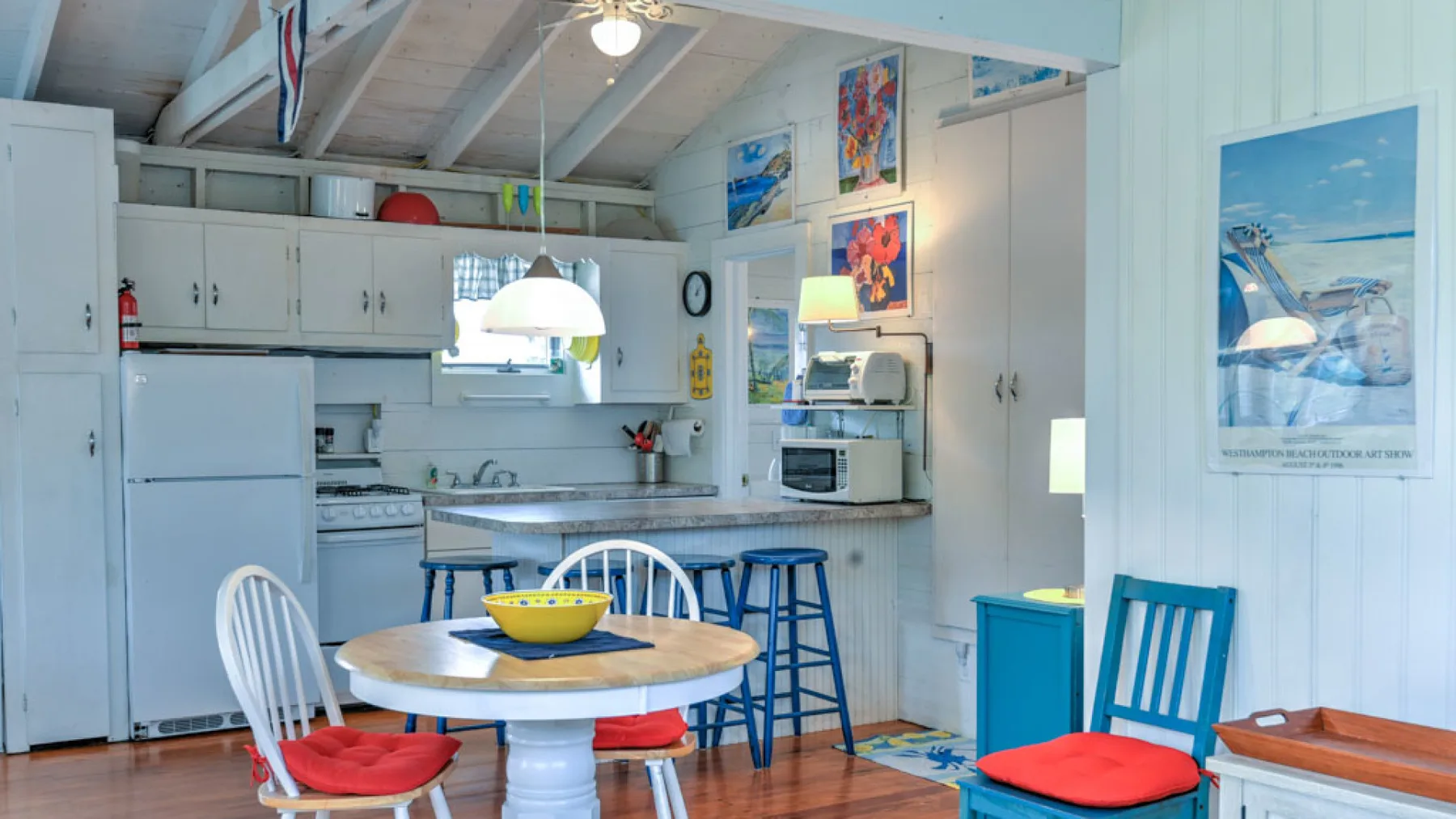 A bright kitchen and dining area with a round table and blue stools.