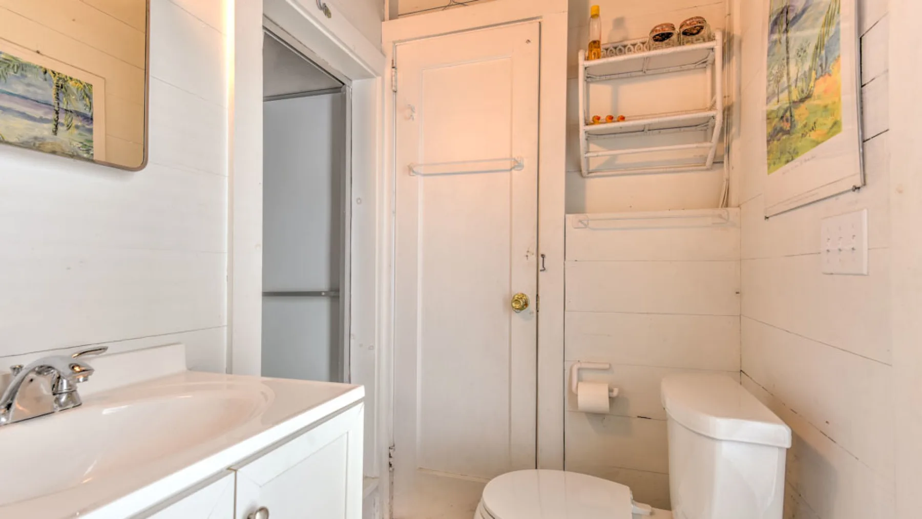 A bathroom with a sink, toilet, and wall shelves.