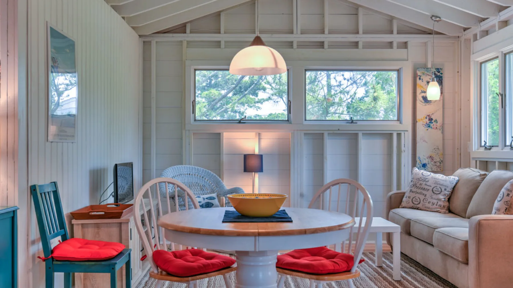 A bright living room with a round dining table and cushioned seating.