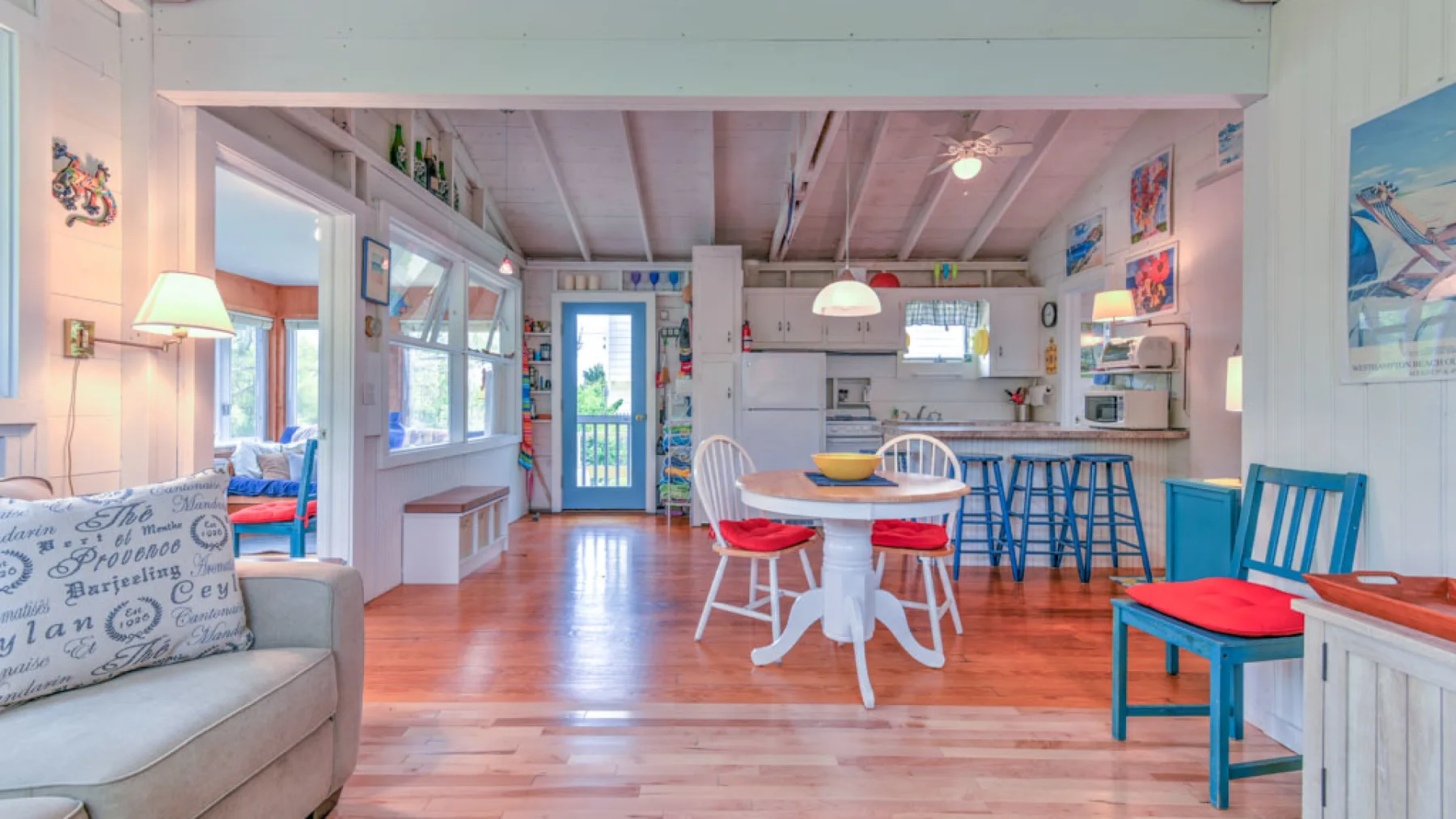 An open-plan dining and kitchen area with a round table and blue counter stools.