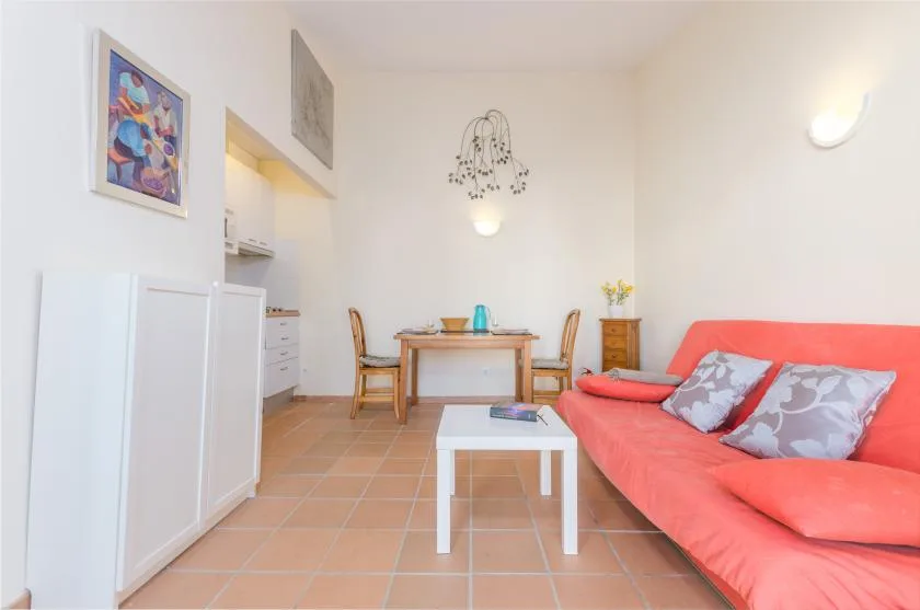 Una luminosa sala de estar y comedor con un sofá rojo y una mesa junto a la cocina.