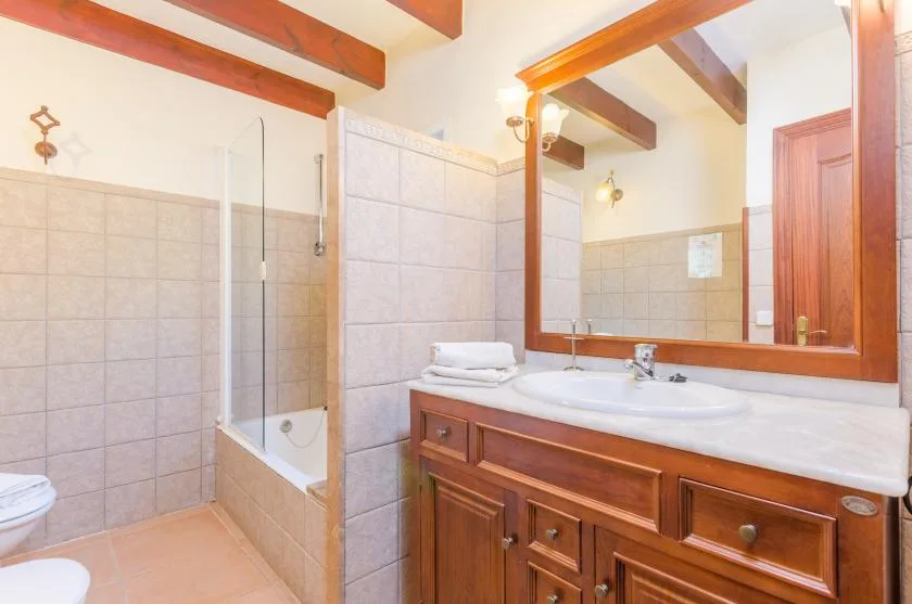 Un baño con azulejos, bañera, tocador de madera y un espejo grande.