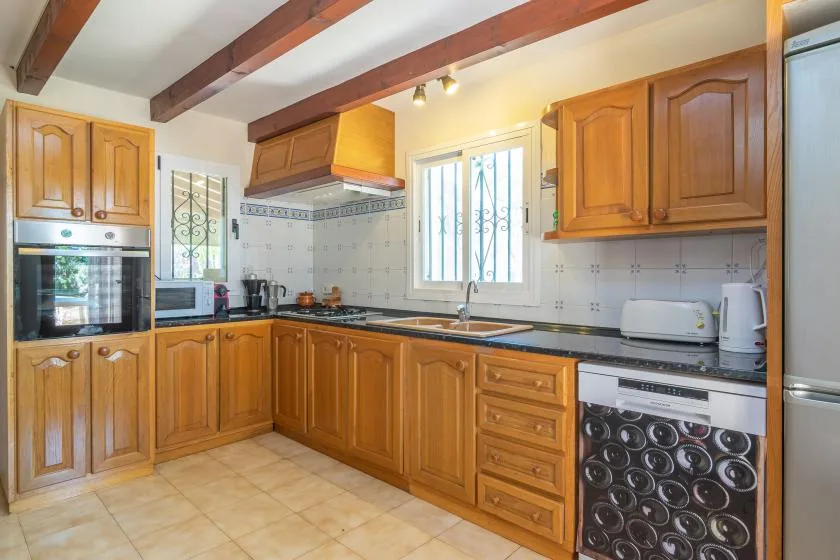 Una cocina con gabinetes de madera, encimeras oscuras y una ventana sobre el fregadero.