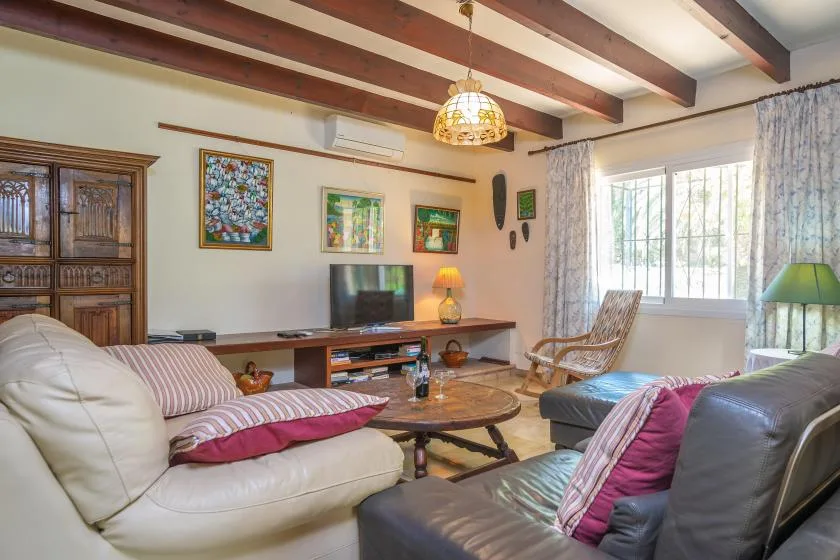 Una sala de estar con asientos, un televisor y ventanas grandes.