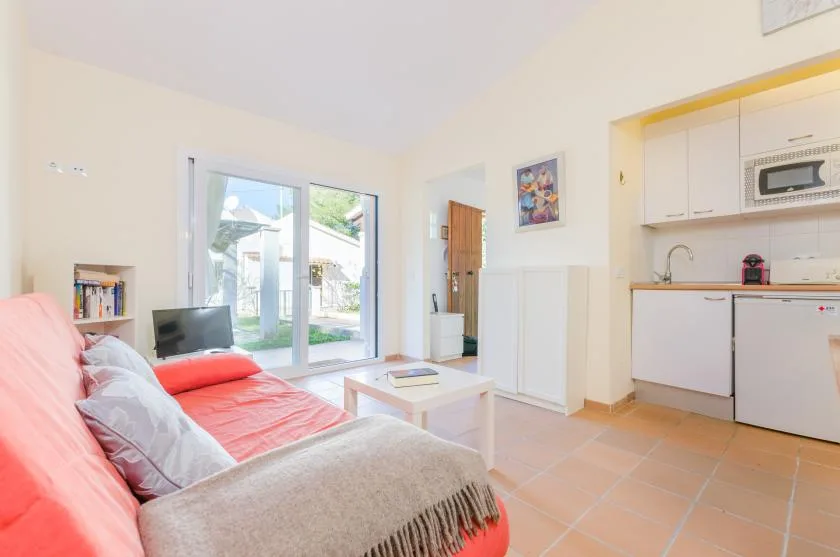 Una luminosa sala de estar con asientos, una mesa de centro y una cocina compacta.