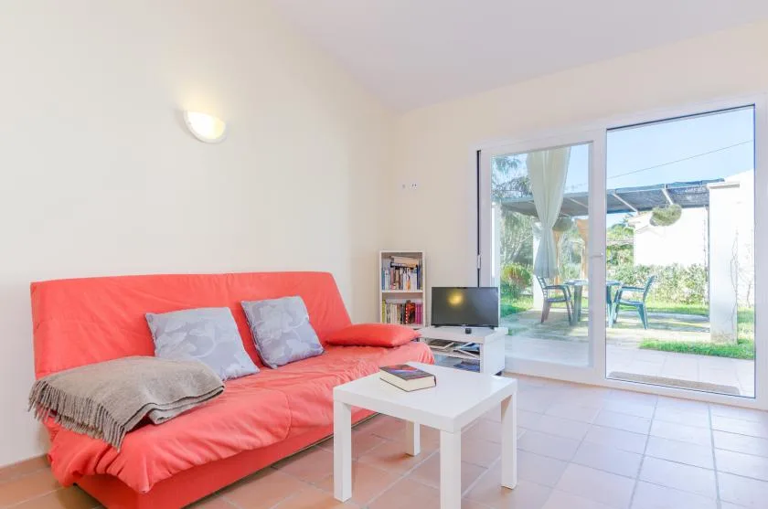 Sala de estar con asientos rojos, una mesa de centro y puertas corredizas de vidrio.
