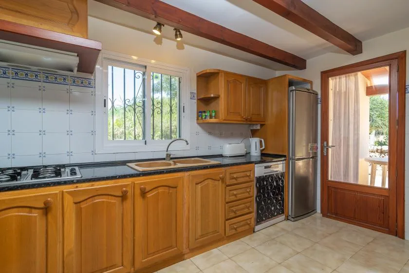 Una cocina con gabinetes de madera, azulejos en la pared y una ventana sobre la encimera.