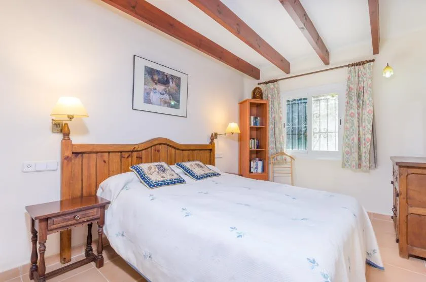 Un dormitorio con una cama de madera, mesas de noche y una ventana.