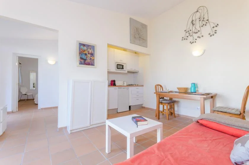Una luminosa estancia diáfana con una cocina compacta, mesa de comedor y zona de estar.