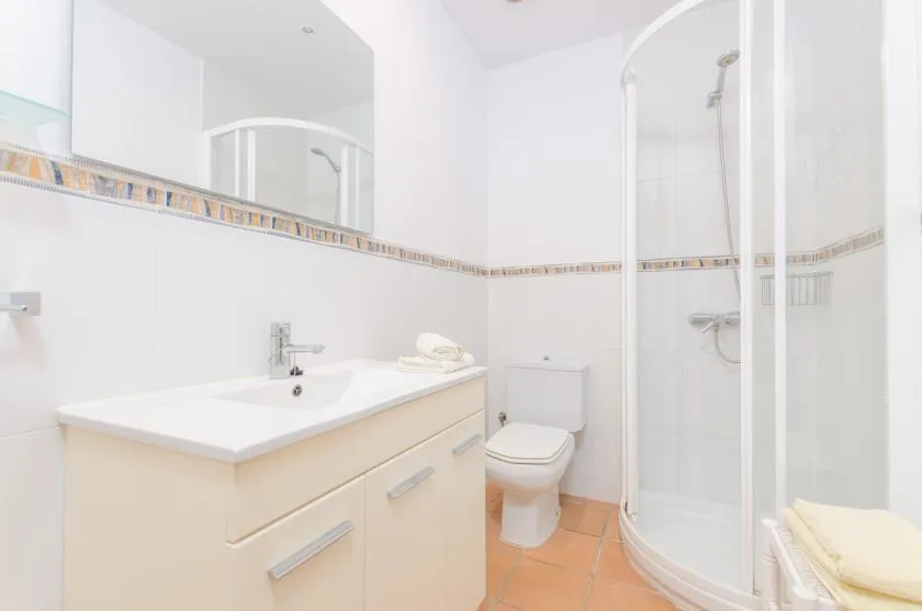 Un baño luminoso con lavabo, mueble y ducha.