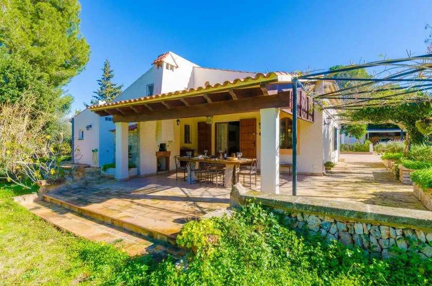 Patio de una casa con asientos al aire libre bajo un techo sombreado.