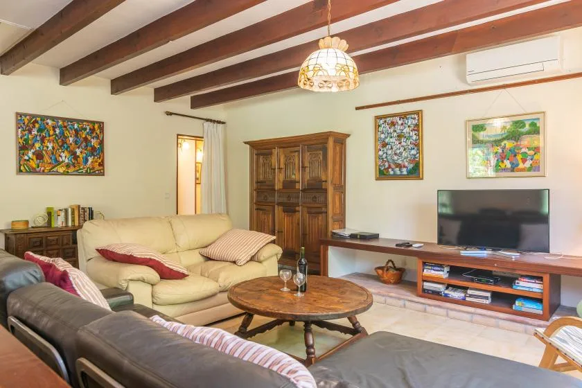 Una sala de estar con asientos, un televisor y cuadros enmarcados.