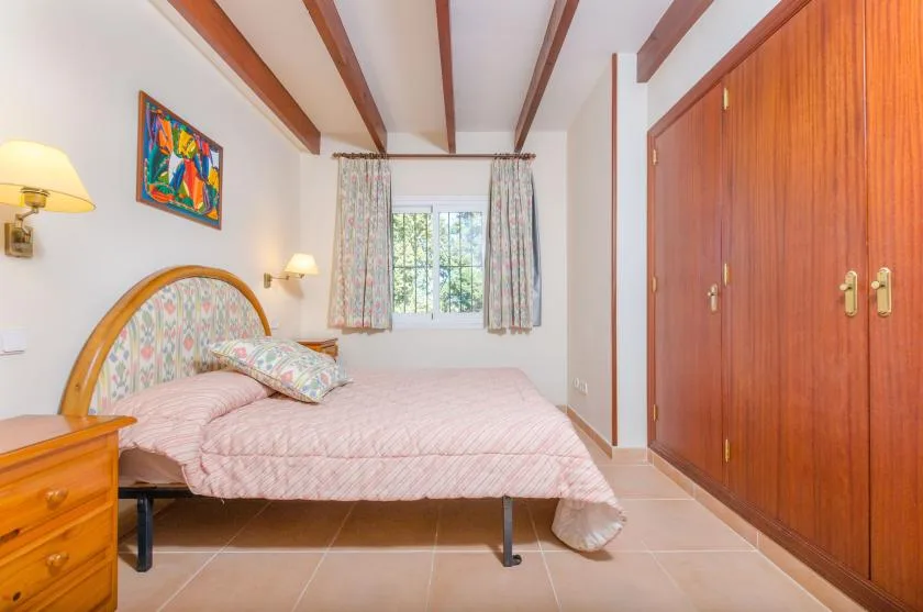 Un dormitorio con una cama bajo una ventana y un armario grande de madera.