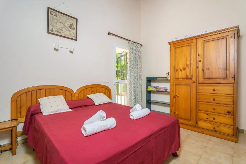 Un dormitorio con una cama doble vestida de rojo y un armario de madera.