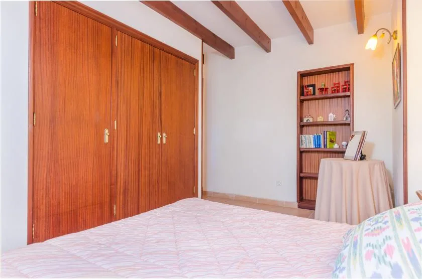 Dormitorio con una cama, un armario de madera y una estantería.