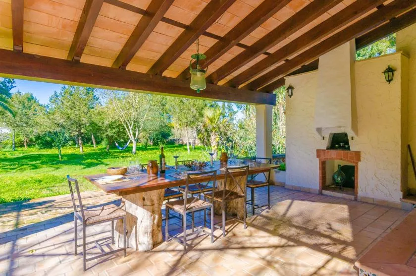 Una zona de comedor exterior cubierta con una mesa de madera frente a un jardín.