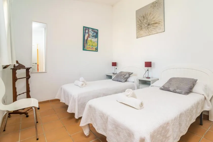 Un dormitorio con dos camas, mesitas de noche y cuadros en la pared.