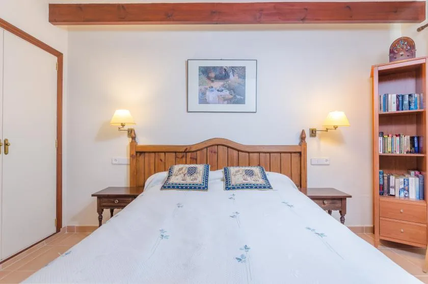 Un dormitorio con una cama de madera, mesillas y una estantería.