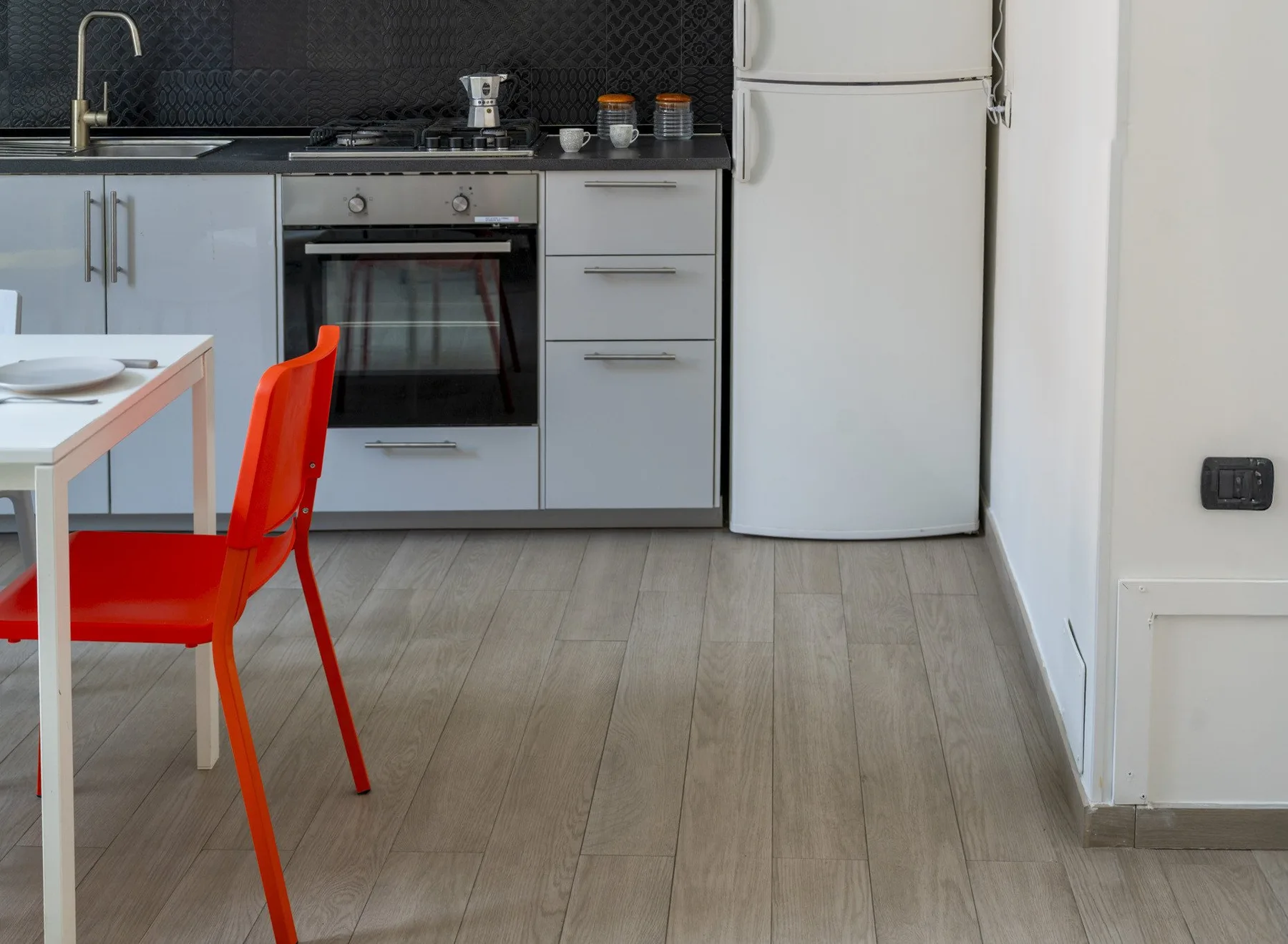 A kitchen with a dining table and bright red seating.