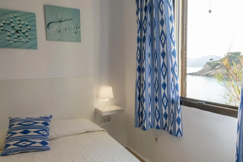 Un dormitorio con una cama junto a una ventana con vistas al agua.