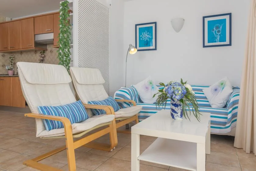 Una sala luminosa con asientos a rayas, dos sillones reclinables y una mesa de centro blanca.