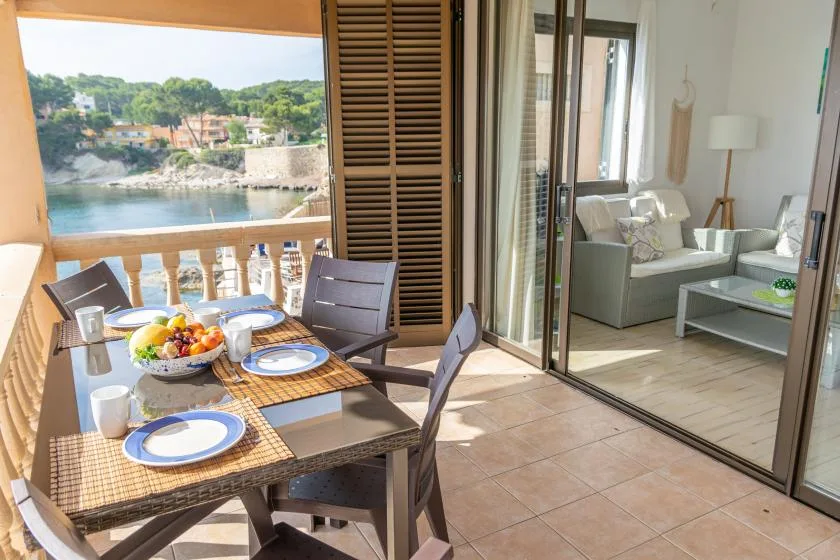 Un comedor en el balcón da al agua, con una mesa preparada para comer.