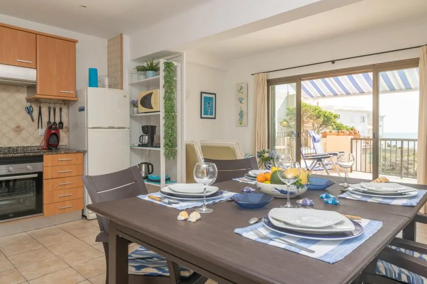 Comedor con la mesa puesta junto a una cocina y puertas corredizas de vidrio.