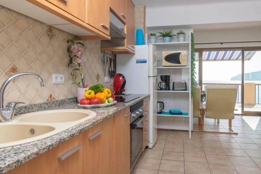 Una cocina con un frutero se abre a un comedor luminoso.