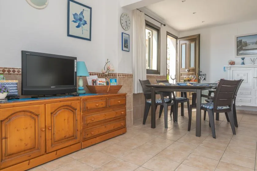 Comedor con una mesa y sillas junto a un mueble de madera y un televisor.