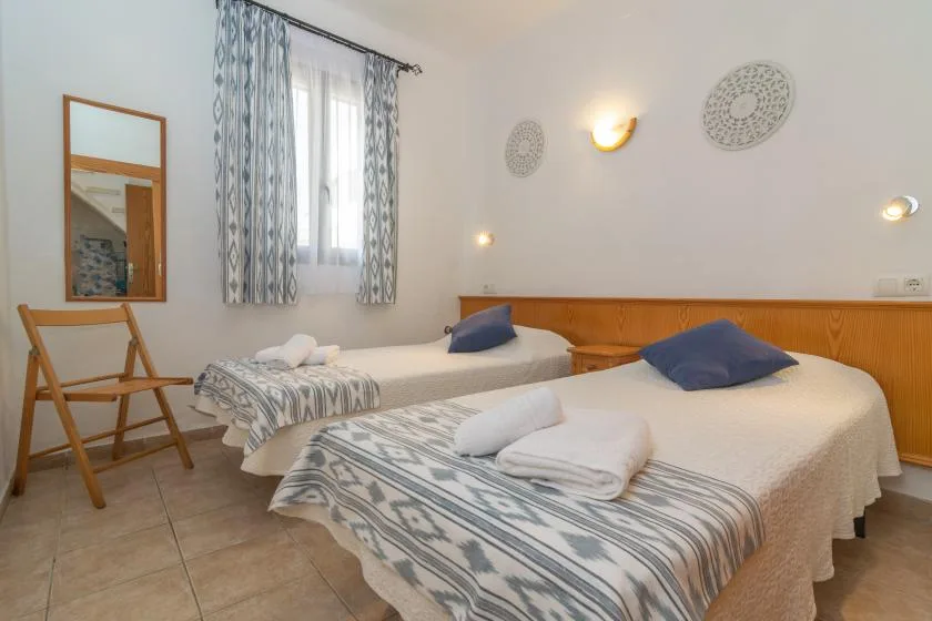 Un dormitorio con dos camas, ropa de cama estampada y una ventana con cortinas.