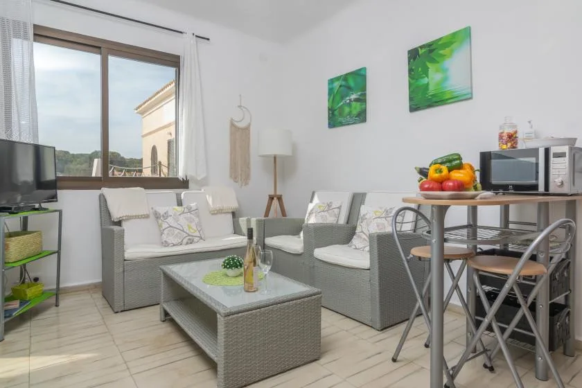 Una sala luminosa con asientos grises, una mesa de centro y un comedor.